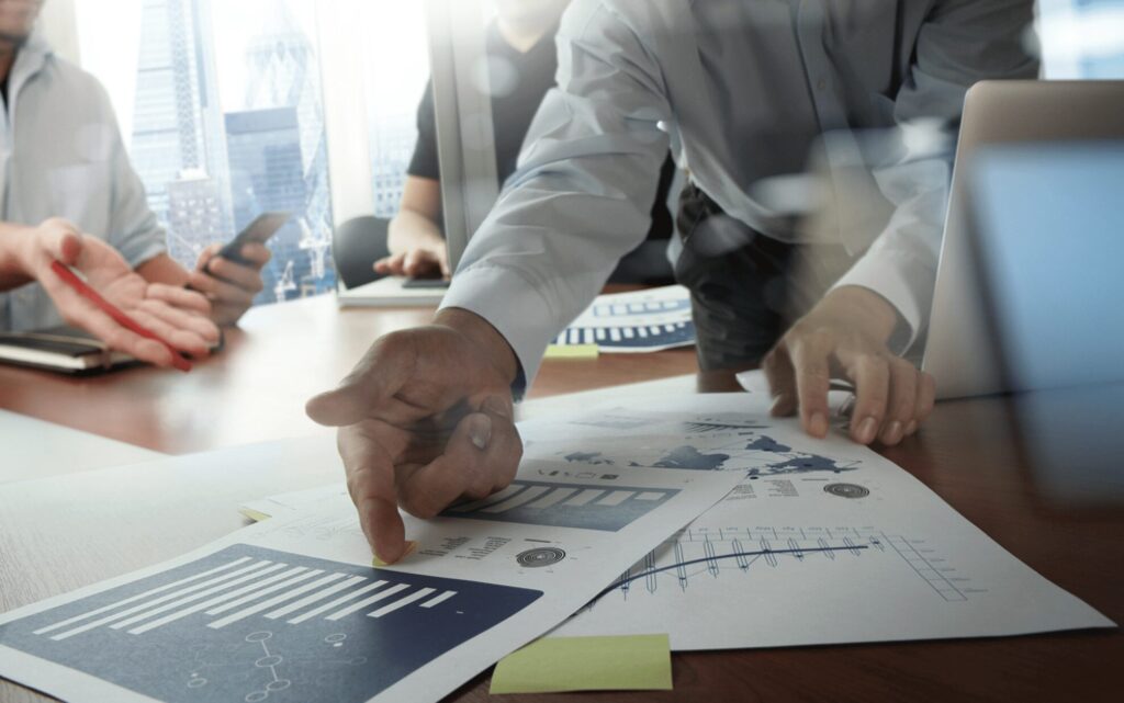 Manufacturing project team reviewing equipment installation plans and Gantt charts in a modern factory office.