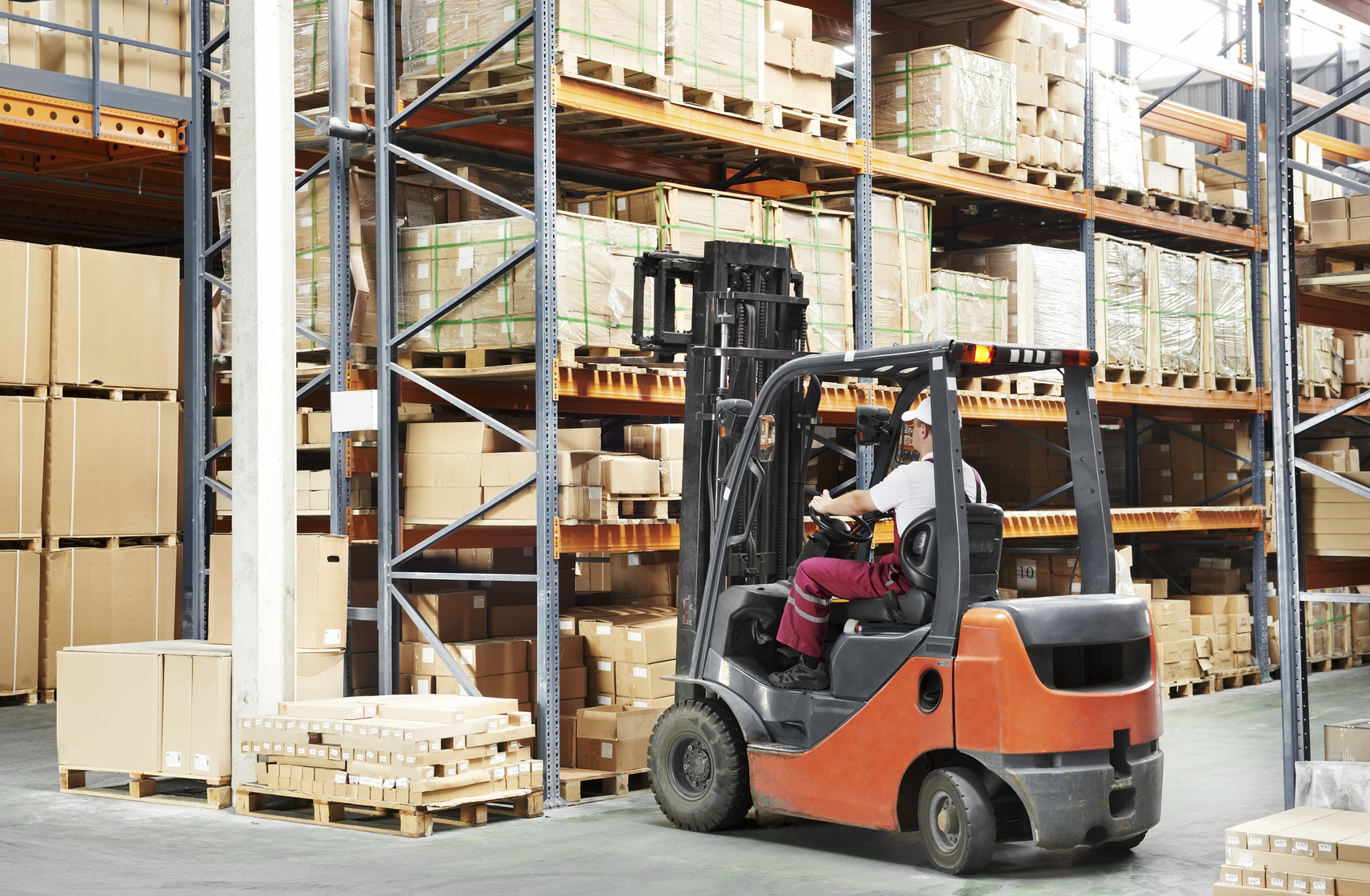 Worker driving a forklift in a warehouse moving boxes